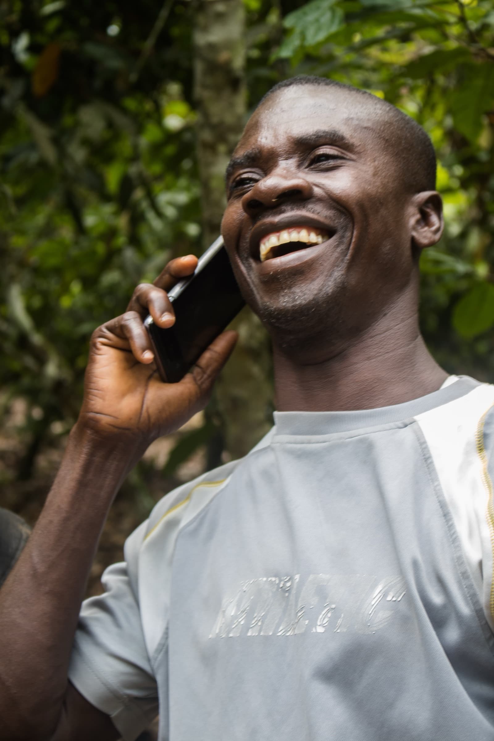 Ghanaian farmer on a phone call amid green farmland